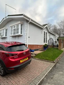 Modern park home with red car showing replacement fasica and guttering